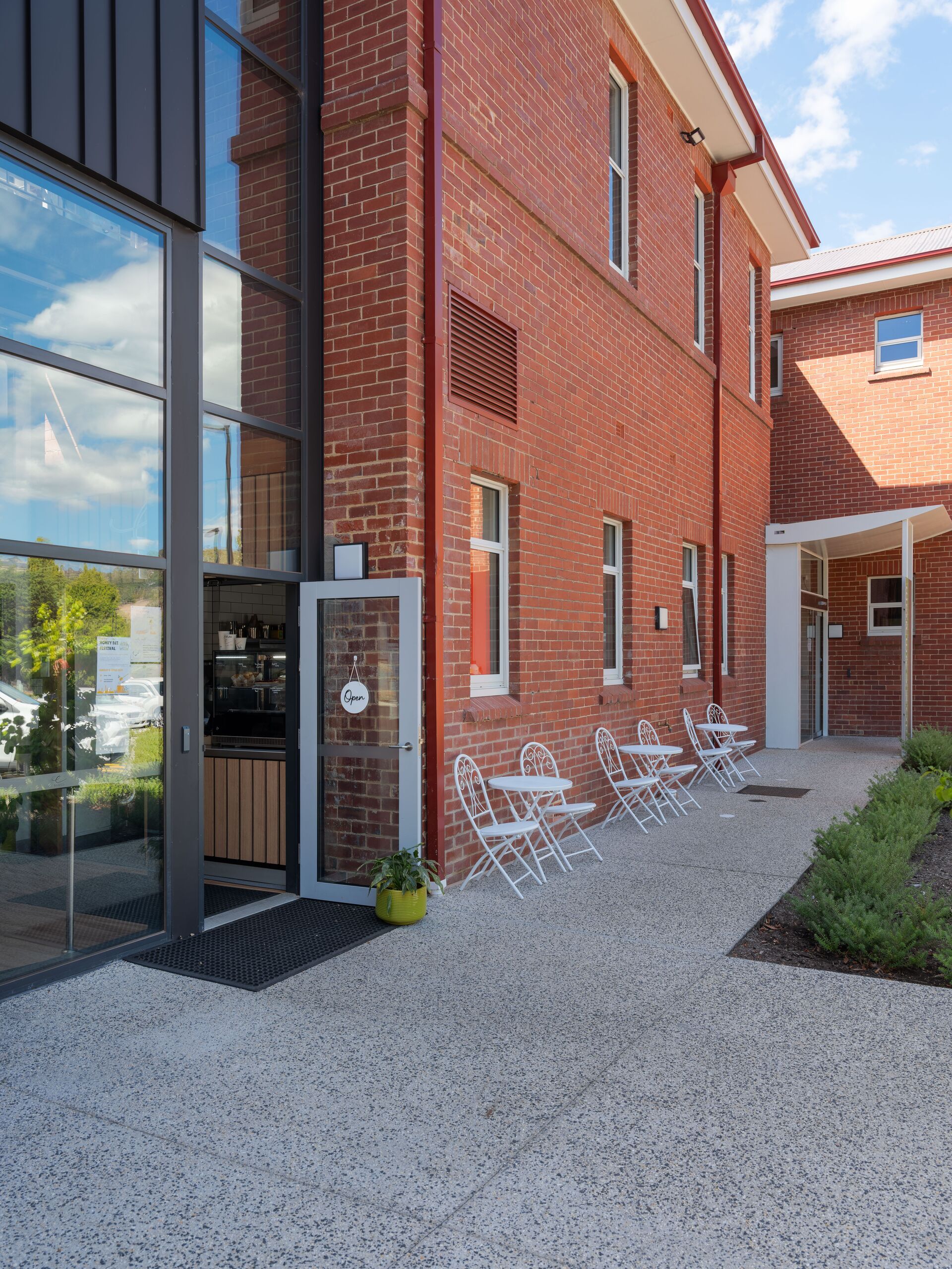 Café terrace and glazed entry beside the restored brick facade