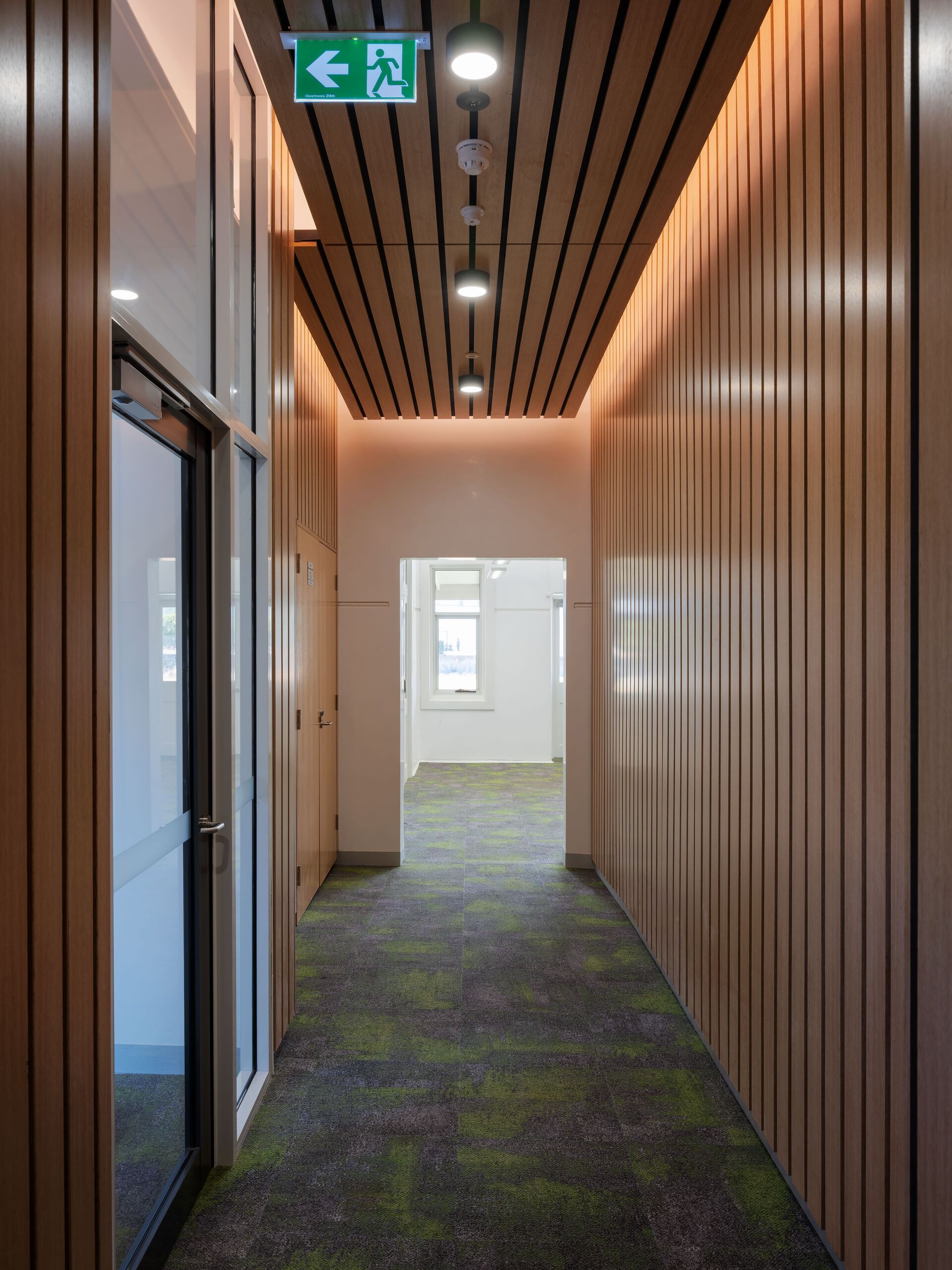 Timber-lined corridor with warm lighting leading to the consulting suites