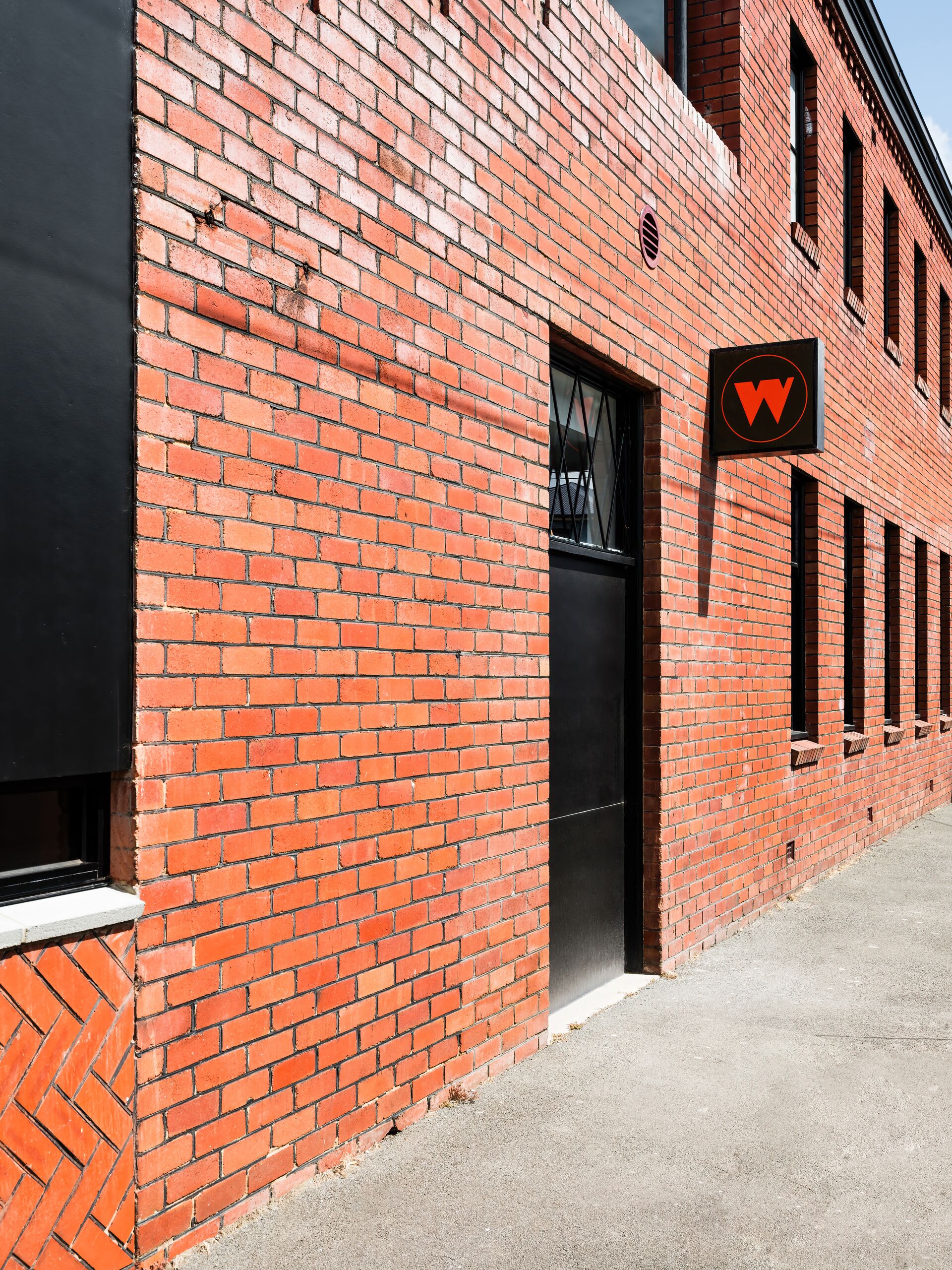 Red brick facade of The Waggon with its W sign, North Hobart