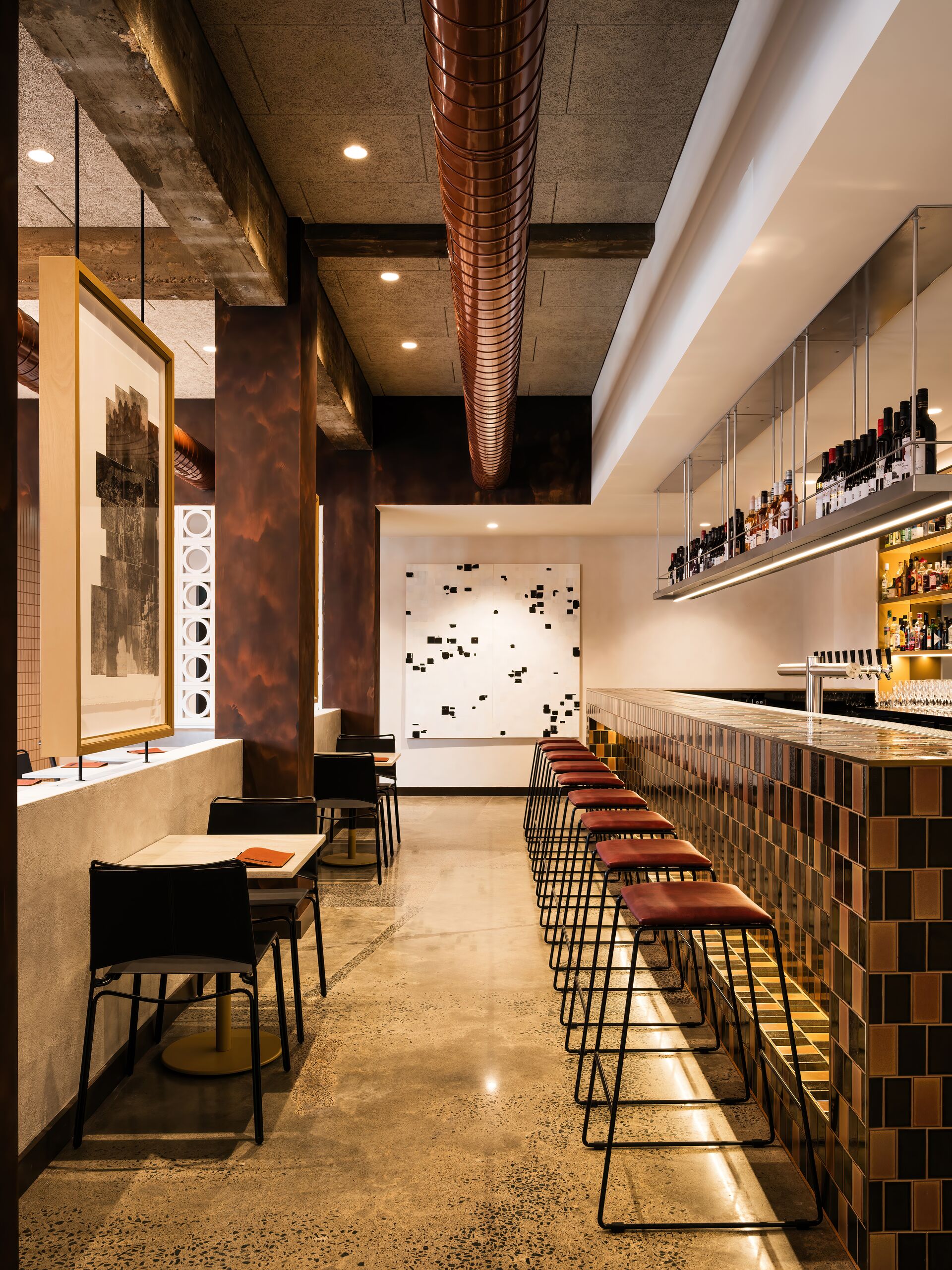 Long bar with tiled front and stools on polished concrete