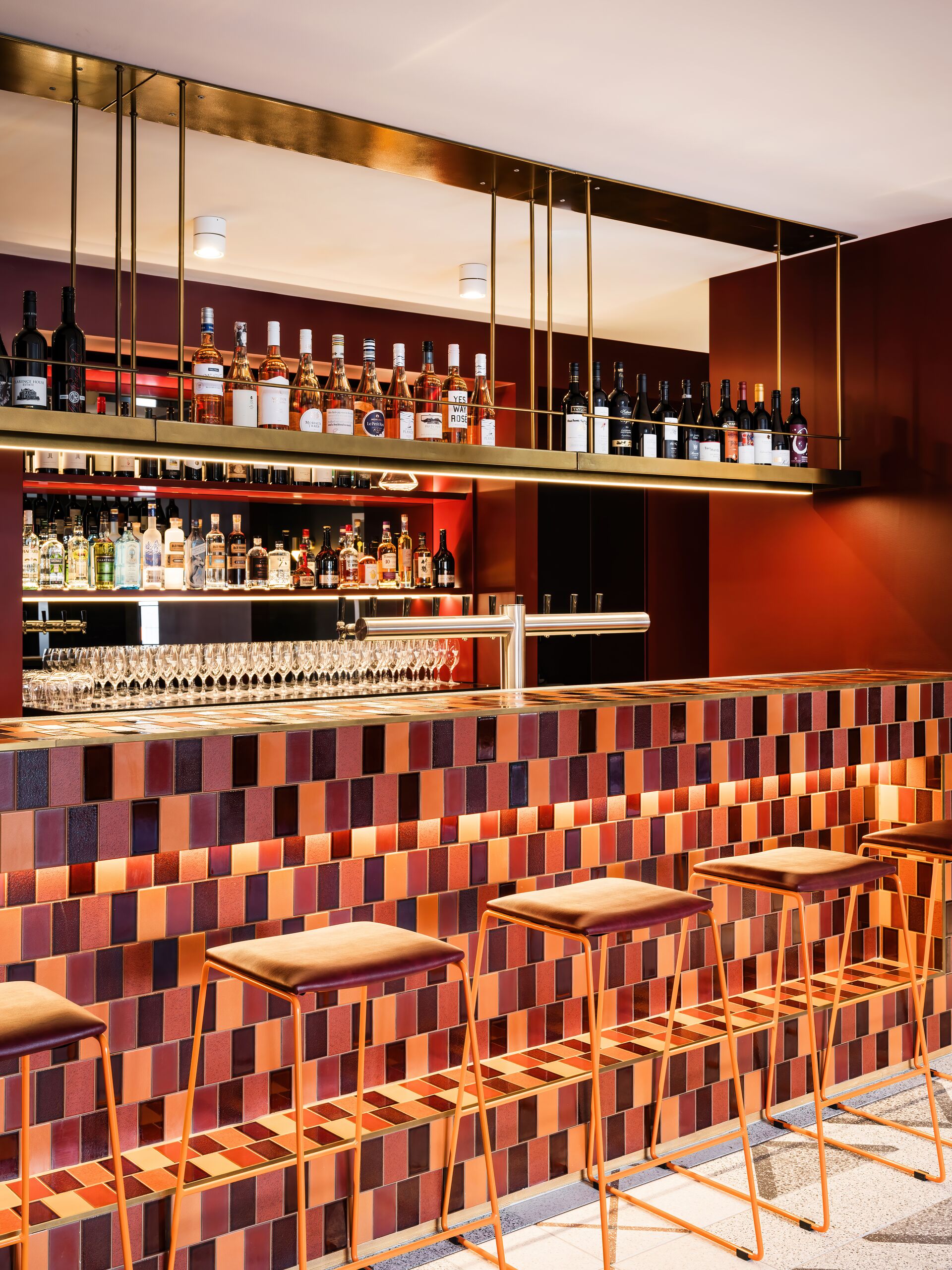 Back bar with brass shelving above a handmade tile bar front