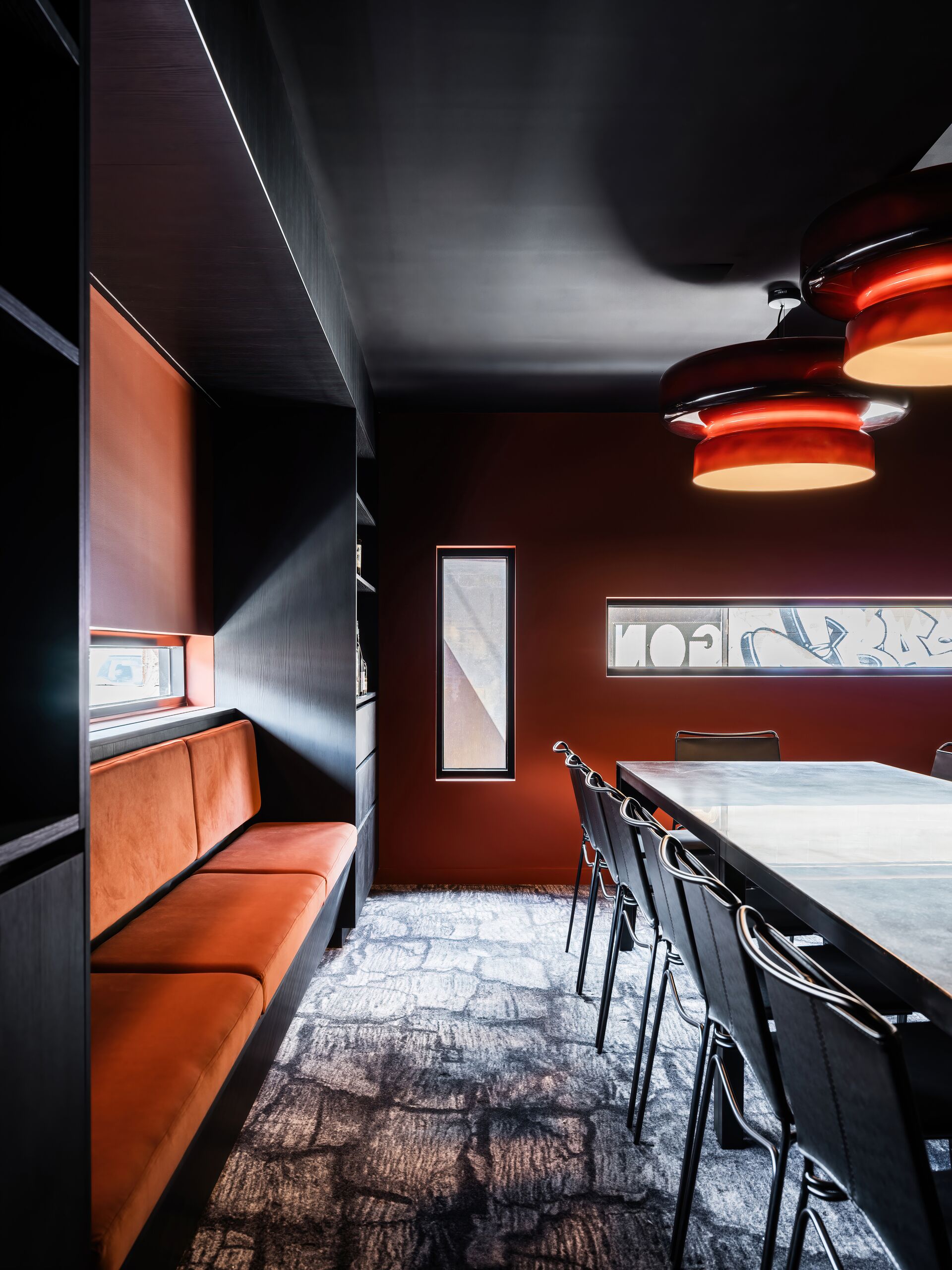 Private dining booth with orange banquette and red pendant lights